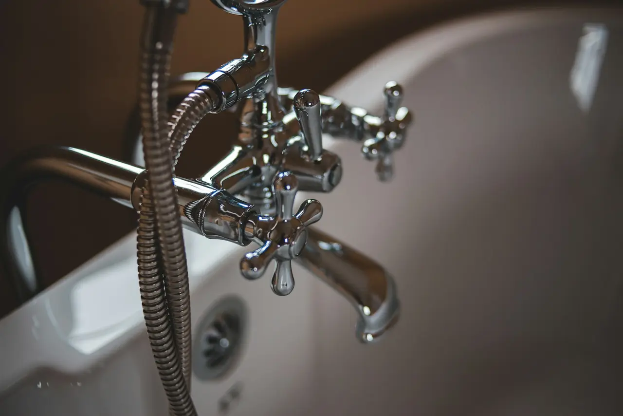 Chrome-plated bath mixer and hand shower on a white bath